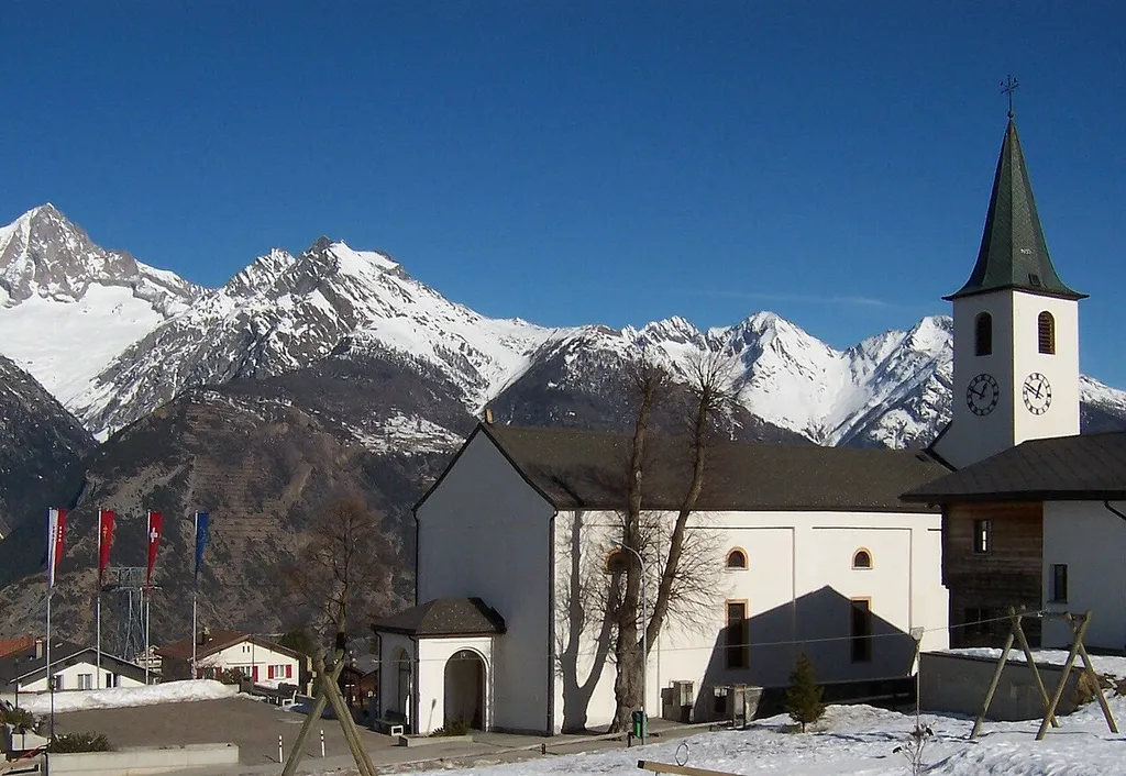 Unterbächer Pfarrkirche Heilige Dreifaltigkeit aus dem Don Bosco-Park gesehen. Ganz links über dem Rhonetal das Bietschhorn.
