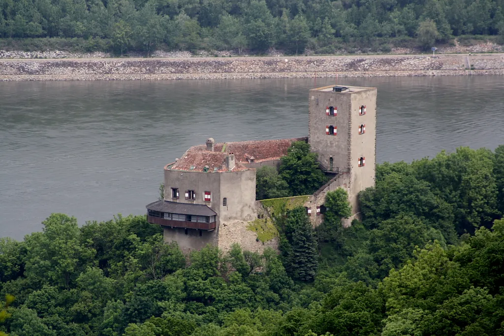 Blick von der Tempelbergwarte auf die Burg Greifenstein (Südwestansicht) und im Hintergrund die Donau.Die im Kern romanische Burg befindet sich nordöstlich von Wien und am nördlichsten Punkt der Alpen, dem „Hangintenstein“ (hängender Stein). Der Name „Hangintenstein“ wurde schon um 900 urkundlich erwähnt und 955 wird das Land bis zu diesem Felsen vom Bayernherzog an das Bistum Passau übergeben. Ihr heutiges Aussehen geht auf die Renovierungen durch Fürst Johann I. von Liechtenstein zu Anfang des 19. Jahrhunderts zurück. Struktur und Charakter der hochmittelalterlichen Anlage blieben dabei erhalten: [1]. Nach einem Kabelbrand im Jahr 2006 wurde die Burg geschlossen: [2]. 2017 kaufte der Unternehmer und Kunstmäzen Ernst C. Strobl die Burg um rd. 2,5 Mio. Euro: [3] und setzte sie wieder instand bzw. ist dabei (Stand: 2021).