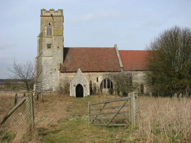 The church of St Andrew in Illington. St Andrew's church > 1758770 has been redundant for almost three decades, ever since the building had been declared too dangerous for use and regular services ceased with a baptism that took place in 1983. The church sits on a slight elevation to the north of Illington Road, on the grounds of Hall Farm, and is adjoined by farm buildings in the west and by fields on all other sides. Only a grassed-over farm track, serving as a public footpath, leads to it > 1758780. When the church was declared redundant the Redundant Churches Fund declined to accept and it took until 1997 for the Norfolk Churches Trust to be able to lease the church and to carry out essential repairs and two services per year are once again being held here. The tower dates from the 14th century. The nave is believed to be older - it has several Norman windows and the arches in the south nave wall > 1758806 - one above the doorway and another around a window - are evidence of the building once having had a south aisle. The baptismal font > 1758824 is believed to date from the 14th century. It was repaired and a text was carved around the top of the bowl at some later time. Pews, pulpit and roof are Victorian. A carved head corbel > 1758814 and a niche in the south east nave are medieval and mark the location of a medieval side altar. The only stained glass in this church is in the east window tracery lights > 1758811 where two St Andrew's crosses can be seen depicted.