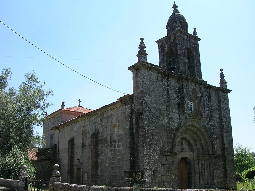 Vista noroeste de la iglesia en la que vemos la amplia portada románica. En los muros norte y sur del ábside conserva dos ventanas saeteras tapiadas.