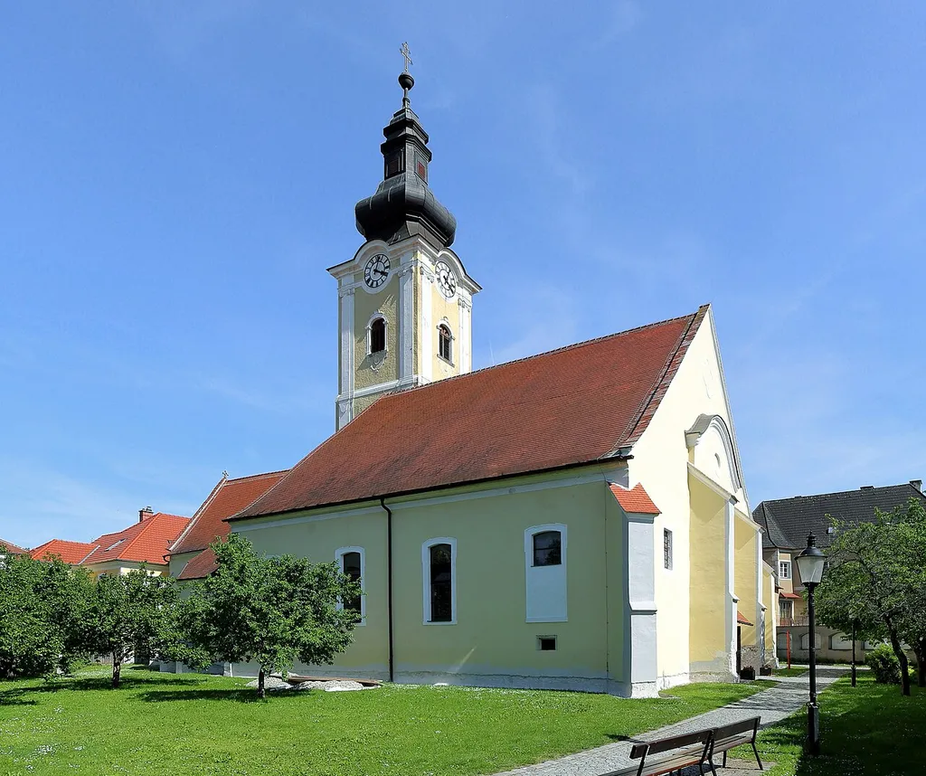 Nordwestansicht der römisch-katholischen Pfarrkirche hl. Stefan in der niederösterreichischen Stadt Mautern an der Donau.Die Kirche wurde in der zweiten Hälfte des 14. Jahrhunderts errichtet, wobei die nördliche Chorseitenkapelle (Totenkapelle) älteren Bestandes ist (Ende 14. Jahrhundert). In den Jahren 1695/96 baute Carlo Antonio Carlone das Langhaus innen um und barockisierte es. Der mächtige, dreigeschossige Kirchturm im südlichen Chorwinkel wurde über mittelalterlichen Kern von 1774 bis 1777 von dem Baumeister Karl Ehmann errichtet.