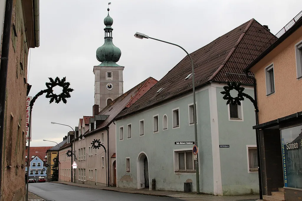 Pressath, Hauptstraße 19 (im Hintergrund Katholische Pfarrkirche St. Georg), ehemaliger Gasthof, zweigeschossiger Walmdachbau mit Korbbogentor und Mauernische: Landkreis Neustadt an der Waldnaabt, Oberpfalz, Bayern (2015)
