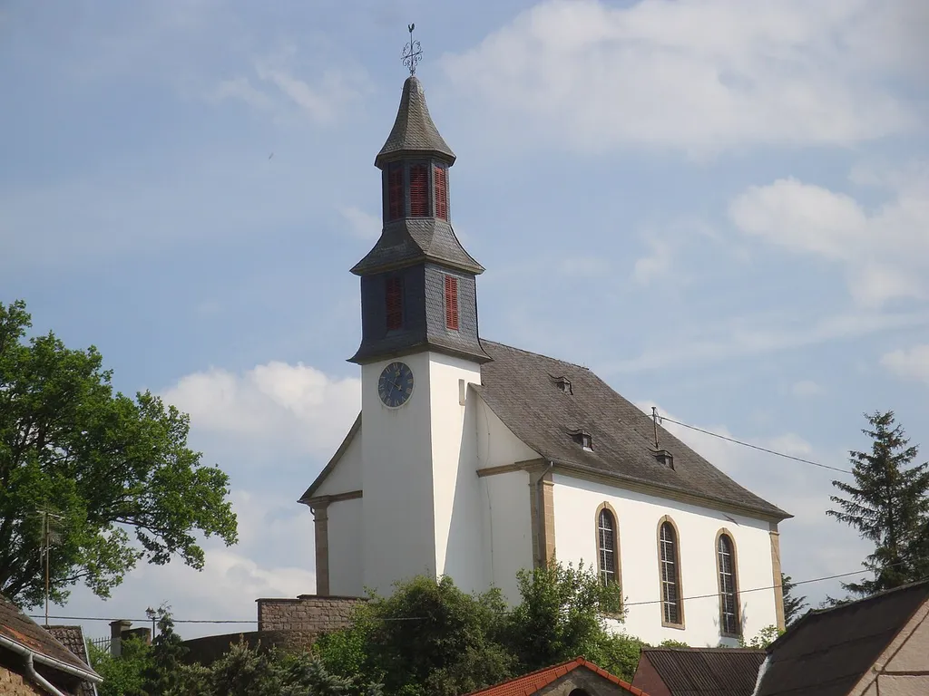 Die Kirche steht auf einer kleinen Anhöhe oberhalb des Ortes. Hinter der Kirche befindet sich der Friedhof.