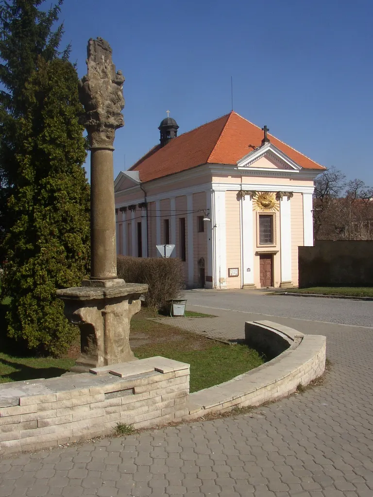 Church of Exaltation of the Holy Cross in Buštěhrad, Czech Republic. In the foreground an 18th century column with relief of Our Lady of Stará Boleslav.