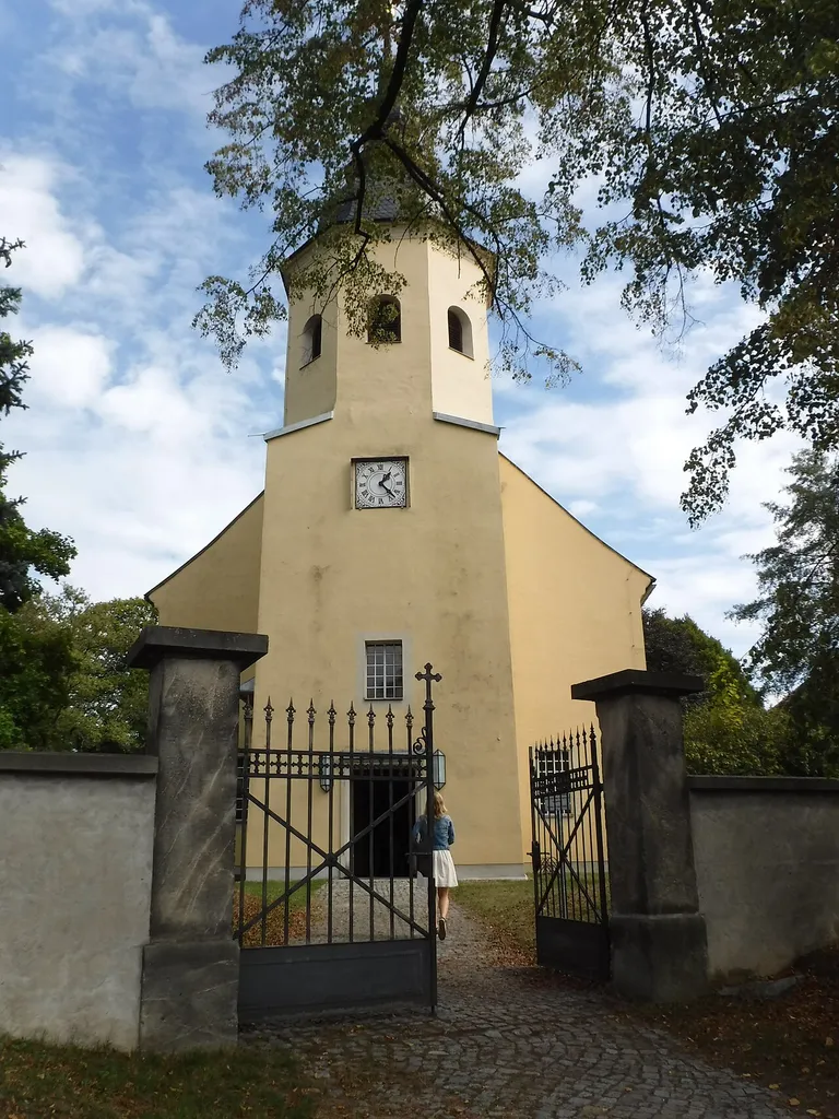 Evangelische Pfarrkirche Wachau (Sachsen) Neubau des Kirchengebäudes anstelle des 1823 abgerissenen alten Baues, Einweihung des neuen Kirchenschiffes am 7. Dezember 1824 durch Johann August Leberecht Hoffmann; der Turm ist 1830 umfangreich saniert worden; 18. Jahrhundert (Grabmale) Baugeschichtlich und ortsgeschichtlich von Bedeutung. Große Saalkirche, 1820–23 neu errichtet unter Verwendung des Turmes von 1689. Putzbau mit gerade geschlossenem Chor, die Ecken angeschnitten, einheitliche Stichbogenfenster. Mächtiger Westturm auf quadratischem Grundriss, im Obergeschoss achteckig mit geschweifter Haube und Helm. Im Innern flachgedeckt, zweigeschossige Emporen an drei Seiten, an den Brüstungsfeldern bäuerliche Malereien mit Szenen aus dem Alten und Neuen Testament (18. Jahrhundert), vermutlich aus dem Erzgebirge. In den Chor ragen zwei Patronatslogen, an der Ostwand Wandmalerei mit Erzengeln mit Gesetzestafeln und Abendmahlskelch von Erhard Ludewig Winterstein aus Leipzig, um 1900. Schlichter klassizistischer Kanzelaltar aus Stuck und Holz, um 1820, Sandsteintaufe, um 1820, Porzellan-Kruzifix, gute Meißener Arbeit, 18. Jahrhundert. Denkmal-ID 09284521
