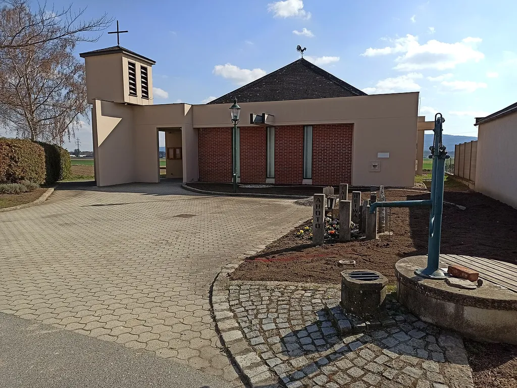 Filialkirche Unterrohrbach, Vorplatz, rechts Brunnen, dahinter ein Friedensdenkmal mit Stelen