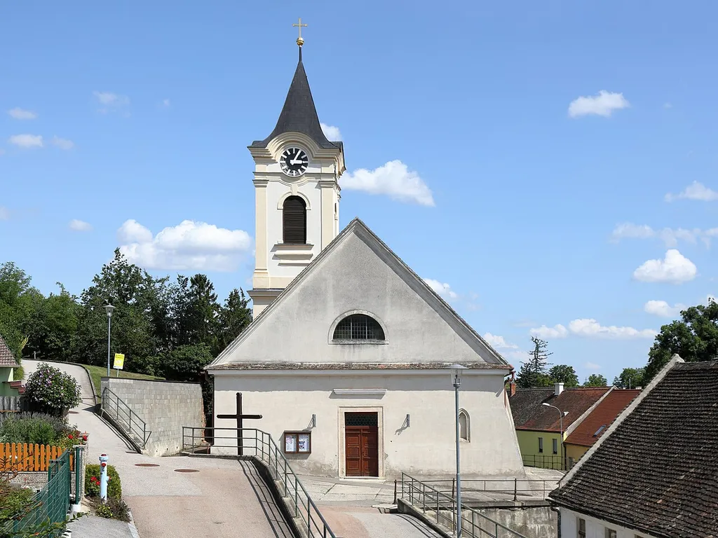 Westansicht der röm.-kath. Pfarrkirche hl. Johannes der Täufer in Mittergrabern, ein Ortsteil der niederösterreichischen Marktgemeinde Grabern.Ursprünglich eine gotische Staffelhallenkirche mit einem Nordturm aus dem 13. Jahrhundert. Später erfolgten frühbarocke Umbauten und um die Mitte des 19. Jahrhunderts fand eine umfassende Erweiterung Richtung Osten statt.