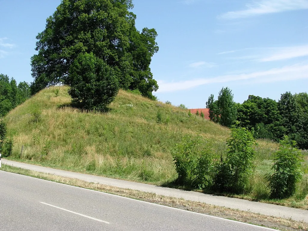 Der Hügel der abgegangenen Burg Ebertshausen aus westlicher Richtung; im Hintergrund ein Teil des Daches des Westflügels von Gut Kaltenbrunn.