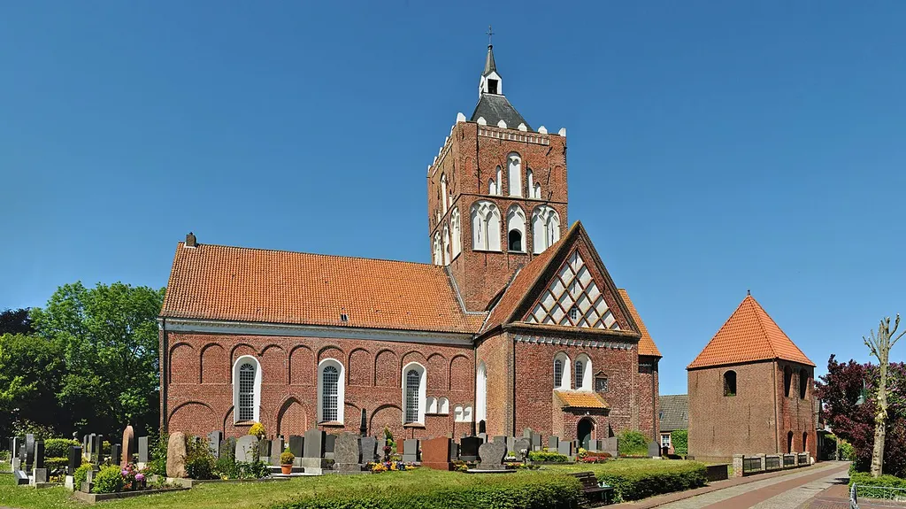 South side of the four naved church named St. Stephanus in Pilsum, Krummhörn (Aurich district, East Frisia, Lower Saxony, Germany), with the Pilsum cemetery in front of it, photographed in a high-resolution panorama.
