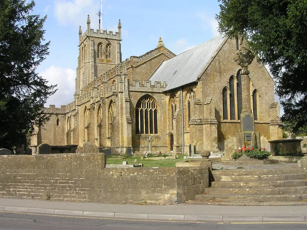 All Saints' parish church, Martock, Somerset, seen from the southeast. The stone cross on the right is the parish war memorial.