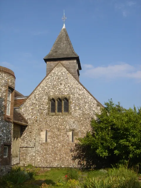 West end of the nave at St Peter's Church, West Blatchington, City of Brighton and Hove, England, showing Norman-era slit windows, modern triple-headed window and bell tower.