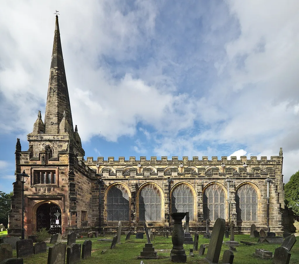 The spire and south side of the grade I listed St Helen's church, Sefton Village. The grade II listed sundial is visible in the foreground.