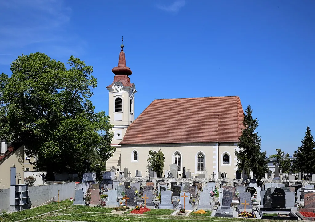 Südsüdwestansicht der katholischen Pfarrkirche hl. Andreas in der niederösterreichischen Stadt Ebreichsdorf. Ein gotischer Sakralbau mit romanischer Kernsubstanz. Der barocke vorgestellte dreizonige Westturm mit Zwiebelhelm wurde 1784 errichtet.