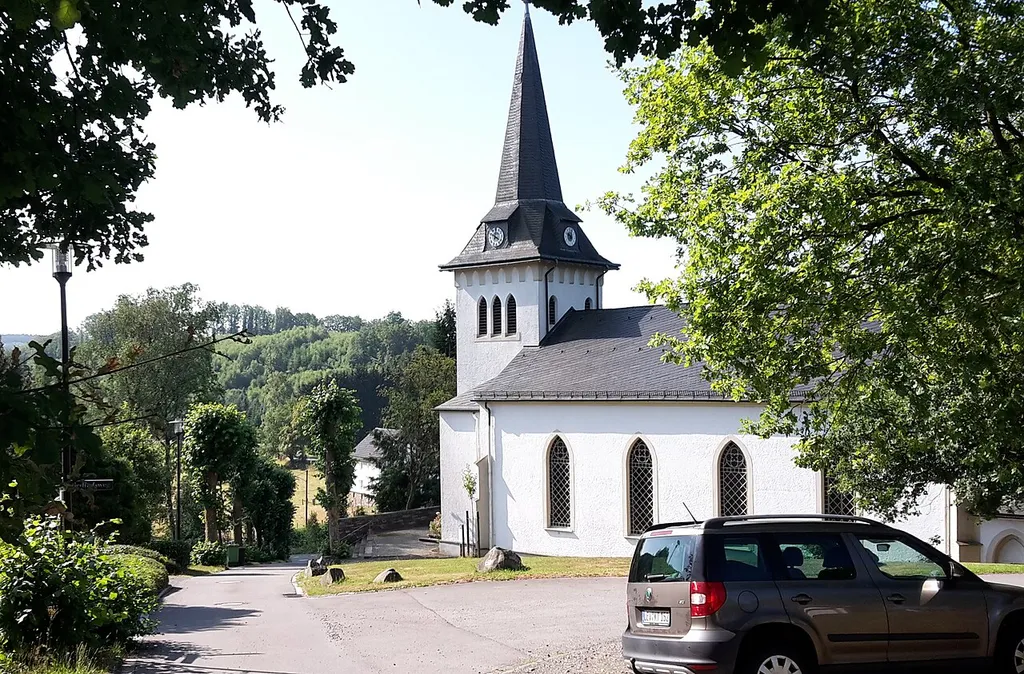 Kirche der Ev. Kirchengemeinde im Oberen Wiehltal, aufgenommen im Sommer 2018 Im Juli 1189 wurde aus Teilen der ev. Kirchengemeinden Eckenhagen und Odenspiel das Pfarrvikariat Heidberg gegründet. Im Frühjahr 1892 wurde mit dem Bau einer Kirche begonnen. Im gleichen Jahr konnte bereits die Einweihung vollzogen werden. Das Pfarrhaus kam 1898 hinzu. Da die Kirche nur einen Dachreiter hatte, wurde 1906 ein Turm angebaut. Nach Vollendung des Turmbaues wurde auch eine Uhr installiert, mit Zifferblättern in alle vier Himmelsrichtungen.